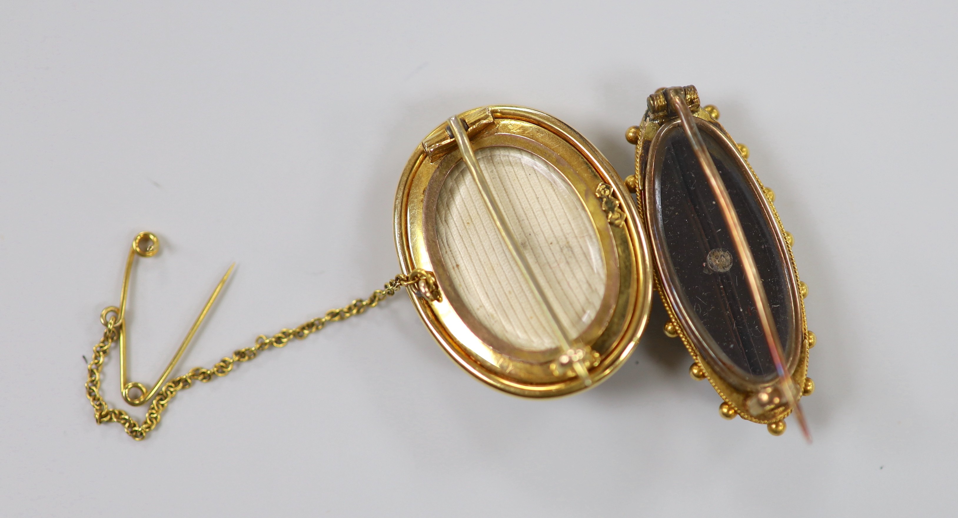 A Victorian 15ct, black onyx and seed pearl set oval mourning brooch, 29mm, gross 10.5 grams, and one other similar yellow metal brooch, 35mm, gross weight 6.3 grams.